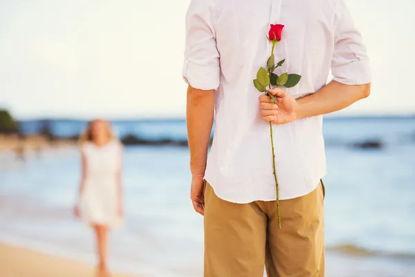 Romantic Young Couple in Love, Man holding surprise rose for bea — Stock Photo, Image