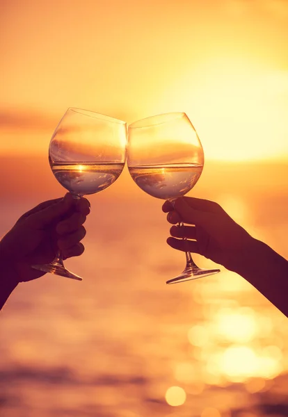 Hombre y mujer clanging copas de vino con champán al atardecer dra —  Fotos de Stock