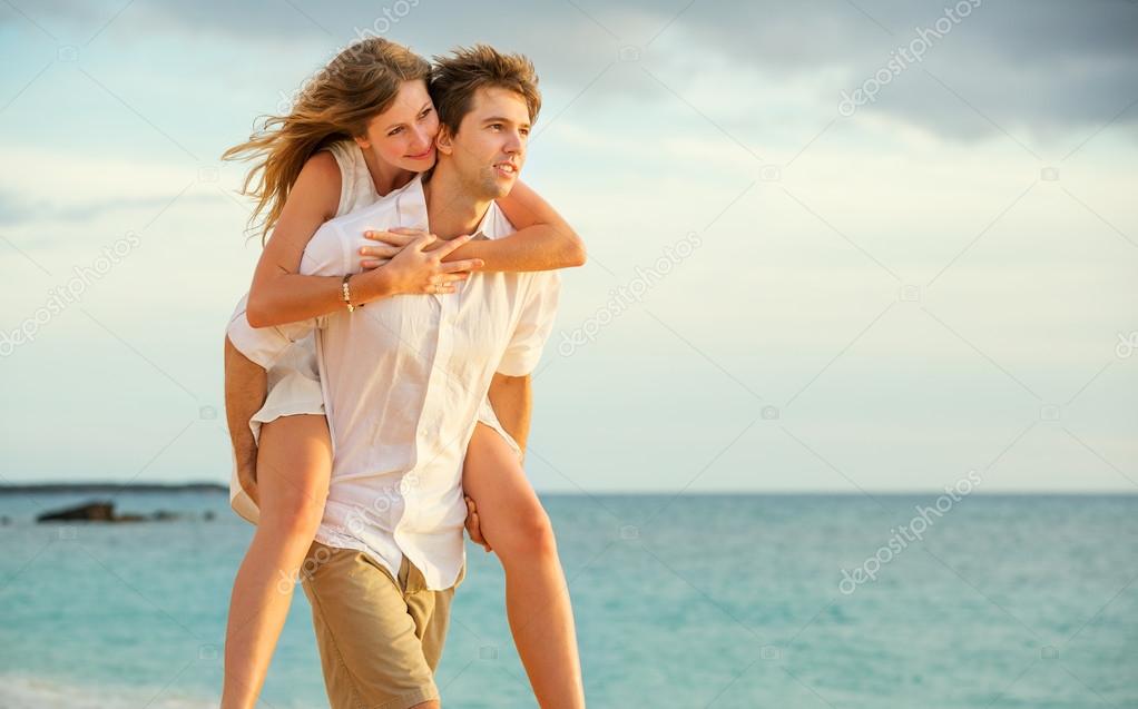 Young couple in love walking on the beach at sunset