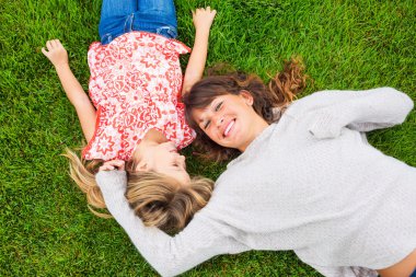 mutlu anne ve kızın rahatlatıcı yeşil çimenlerin üzerinde dışında. harcama