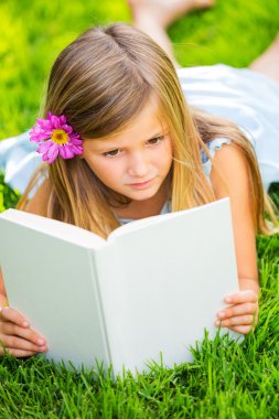 sevimli küçük kız çimlerin üzerine dışında kitap okuma