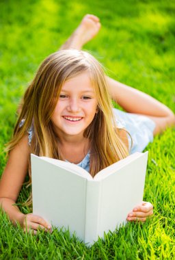 sevimli küçük kız çimlerin üzerine dışında kitap okuma