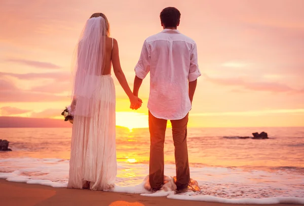 Noiva e noivo, desfrutando do incrível pôr do sol em um belo tropical — Fotografia de Stock