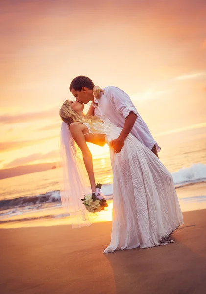 Panny młodej i pana młodego, całuje na zachód słońca na plaży tropikalnej — Zdjęcie stockowe