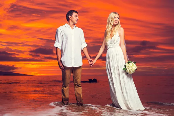 Braut und Bräutigam genießen einen atemberaubenden Sonnenuntergang auf einem wunderschönen tropischen — Stockfoto