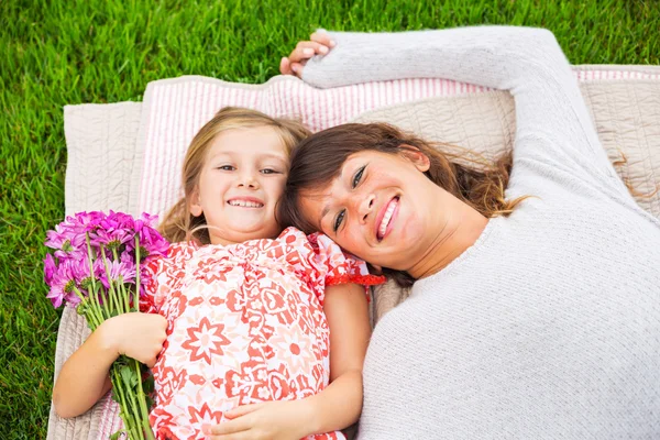 Feliz madre e hija relajándose fuera en la hierba verde. Gastar —  Fotos de Stock