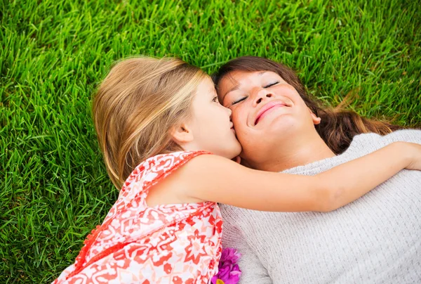 Gelukkig moeder en dochter ontspannen buiten op gras. besteden — Stockfoto