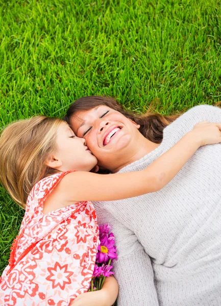 Feliz madre e hija relajándose fuera en la hierba verde. Gastar —  Fotos de Stock