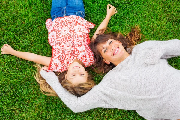 Mãe feliz e filha relaxando lá fora na grama verde. Despesas — Fotografia de Stock