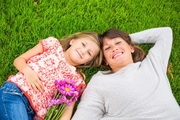 Feliz madre e hija relajándose fuera en la hierba verde. Gastar —  Fotos de Stock