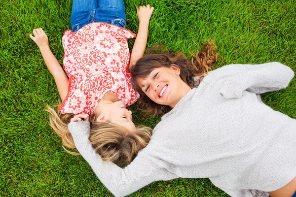 Mutlu anne ve kızın rahatlatıcı yeşil çimenlerin üzerinde dışında. harcama — Stok fotoğraf