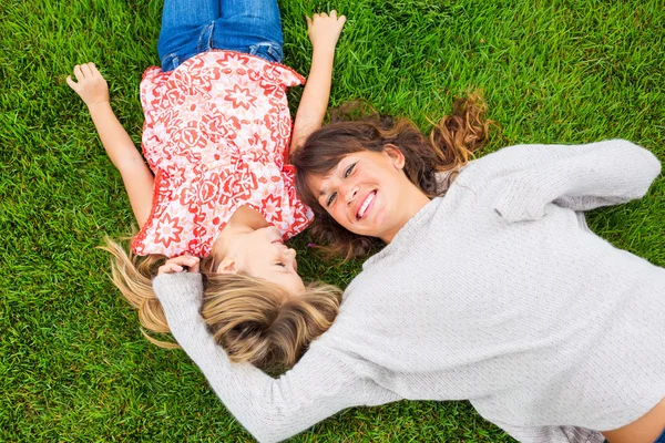 Mère et fille heureuses se relaxant dehors sur l'herbe verte. Dépenser — Photo