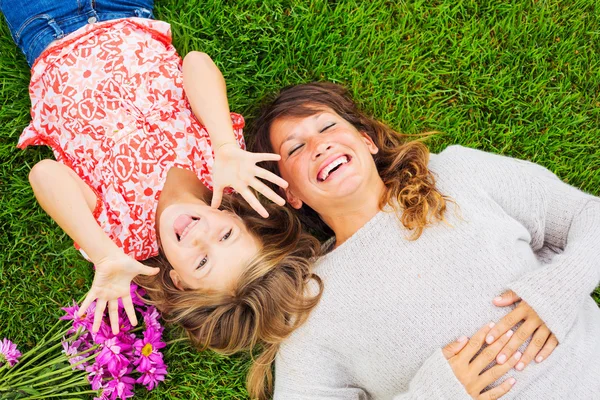 Mãe feliz e filha relaxando lá fora na grama verde. Despesas — Fotografia de Stock