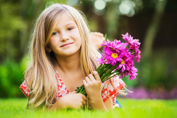 一个微笑的小女孩躺在绿草上的画像 — 图库照片