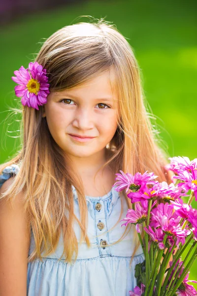 Portret van een glimlachende schattig klein meisje met bloemen — Stockfoto