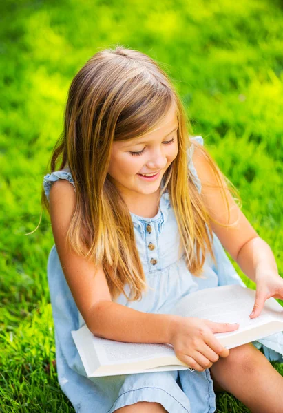 Cute little girl reading book outside on grass — Stock Photo, Image