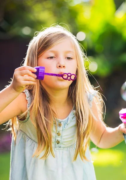 Мила маленька дівчинка дме мильні бульбашки — стокове фото