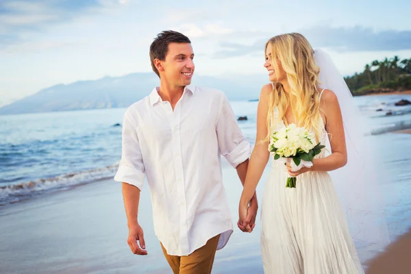 Noiva e noivo, caminhando em uma bela praia tropical ao pôr do sol — Fotografia de Stock