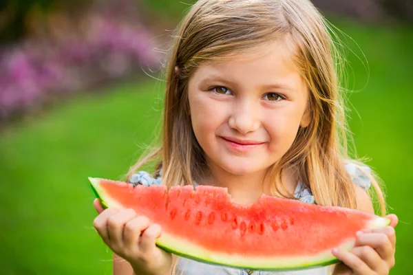 Adorable blonde girl eating watermelon outdoors — Stock Photo, Image