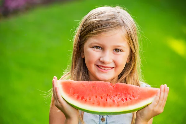 Adorable blonde girl eating watermelon outdoors — Stock Photo, Image