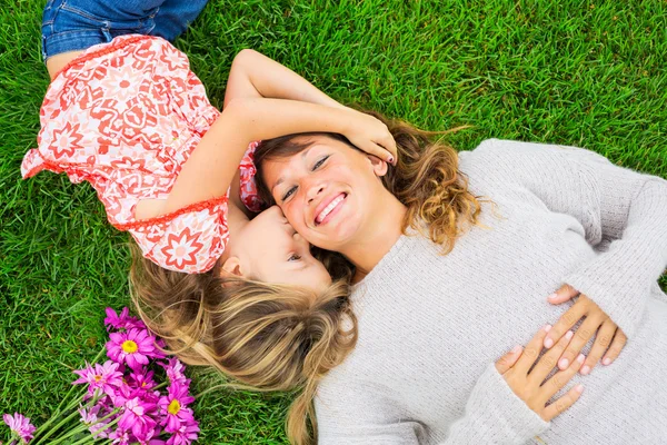 Moeder en dochter liggen samen buiten op gras — Stockfoto