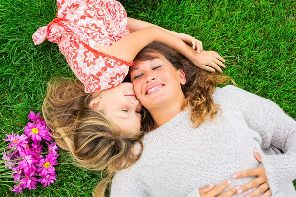 Moeder en dochter liggen samen buiten op gras — Stockfoto