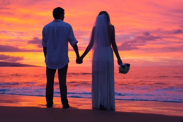 Net getrouwd stel bedrijf handen op het strand bij zonsondergang — Stockfoto