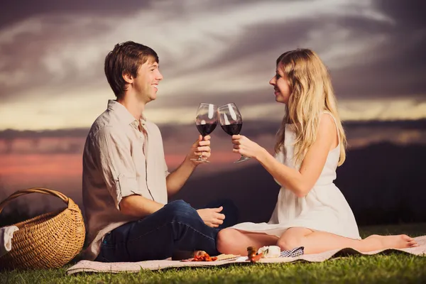 Paar trinkt ein Glas Wein beim romantischen Picknick bei Sonnenuntergang — Stockfoto