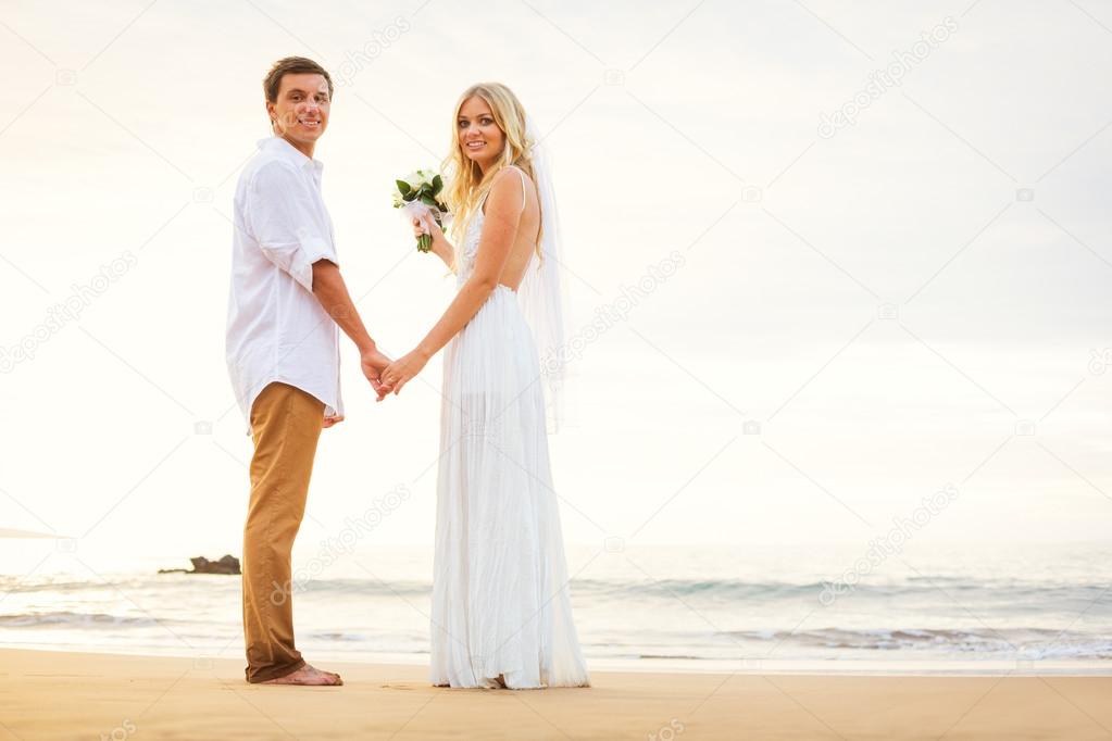 Just married couple holding hands on the beach