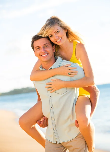 Casal atraente brincando na praia ao pôr do sol — Fotografia de Stock