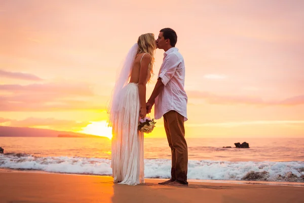 Małżeństwo, panny młodej i pana młodego, całuje na zachód słońca na pięknym — Zdjęcie stockowe