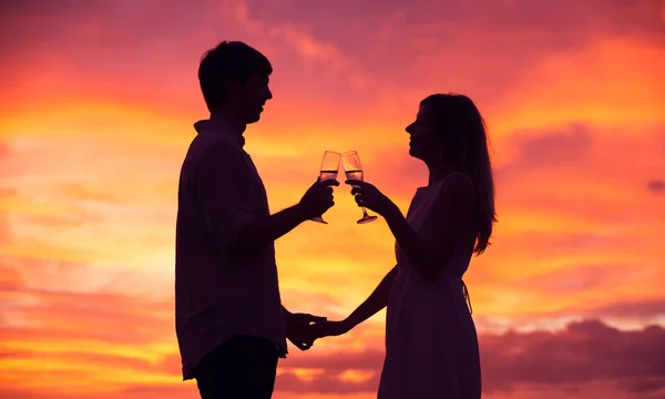 Silhouette pár pezsgőt isznak a naplemente — Stock Fotó
