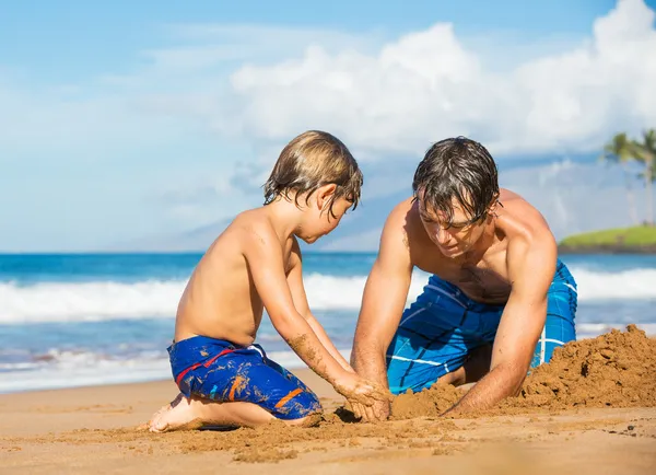Far och son spelar tillsammans i sanden på tropisk strand — Stockfoto