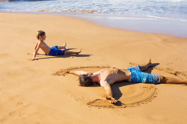 Far och son spelar tillsammans i sanden på tropisk strand — Stockfoto