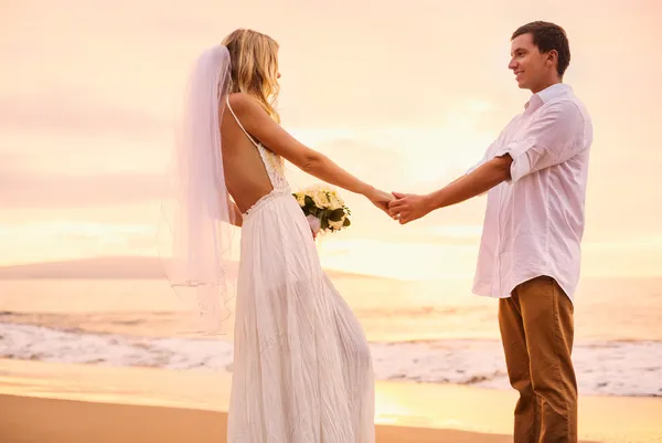Braut und Bräutigam am Strand bei Sonnenuntergang — Stockfoto