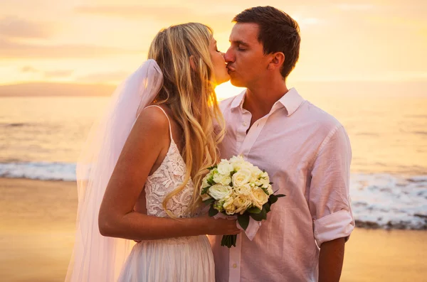 Braut und Bräutigam am Strand bei Sonnenuntergang — Stockfoto