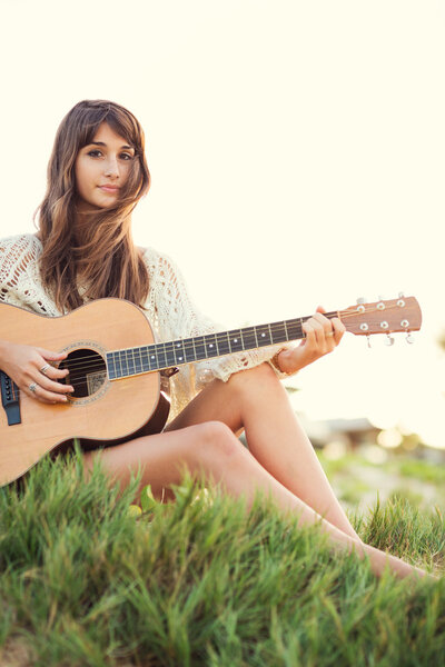 Beautiful young woman playing guitar on beach