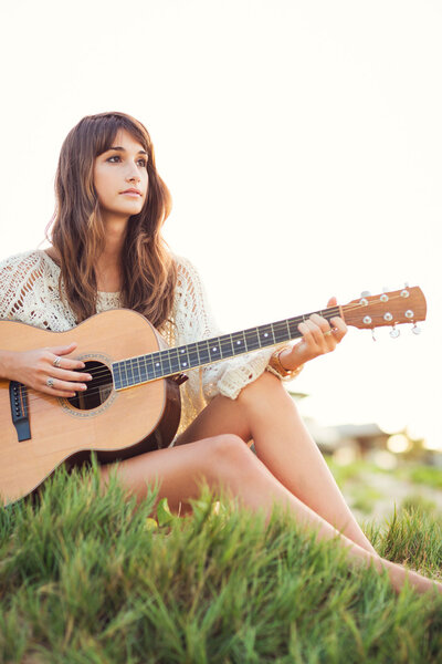 Beautiful young woman playing guitar on beach