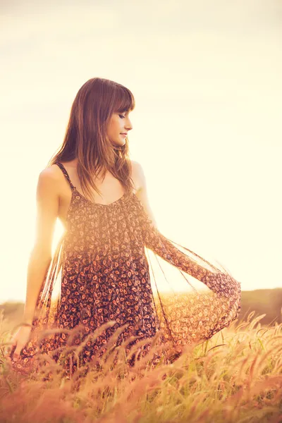 Романтическая модель в солнечном платье на золотом поле на закате — стоковое фото