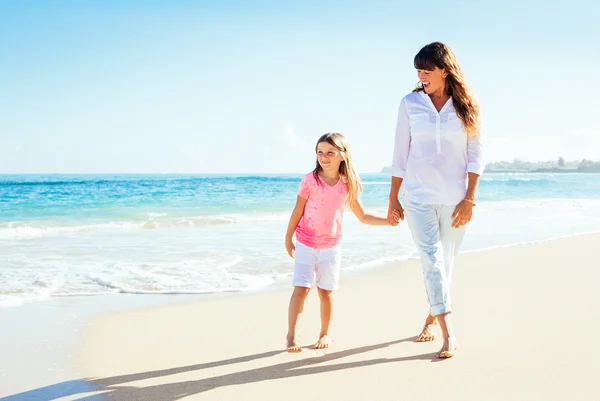 Lycklig mor och unga dotter promenerar på stranden — Stockfoto