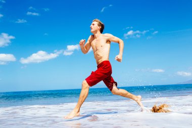 Kumsalda koşan atletik bir adam