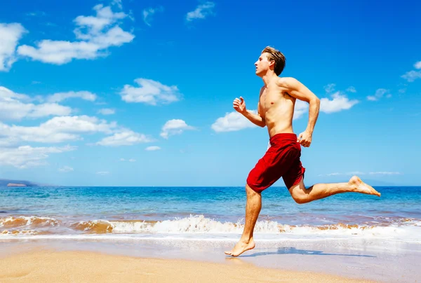 Sportlicher Mann läuft am Strand — Stockfoto