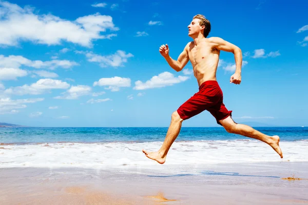 Sportlicher Mann läuft am Strand — Stockfoto