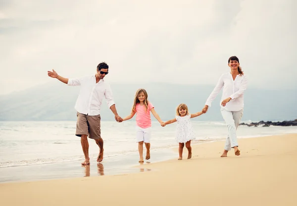 Gelukkige familie veel plezier wandelen op het strand bij zonsondergang — Stockfoto