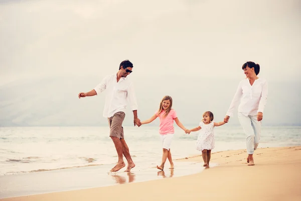 Счастливая семья весело гуляет по пляжу на закате — стоковое фото
