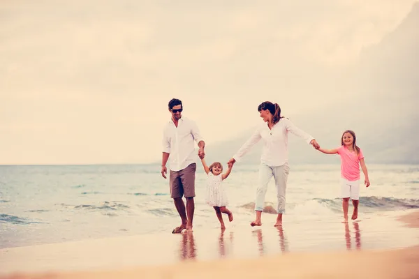幸福年轻的家庭有乐趣在日落时分在海滩上行走 — 图库照片
