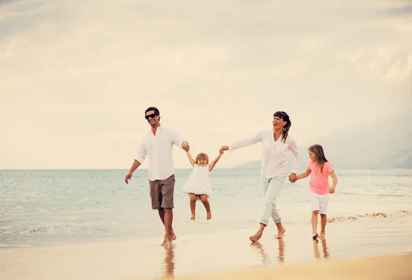 Szczęśliwą rodziną bawić się na spacery na plaży o zachodzie słońca — Zdjęcie stockowe