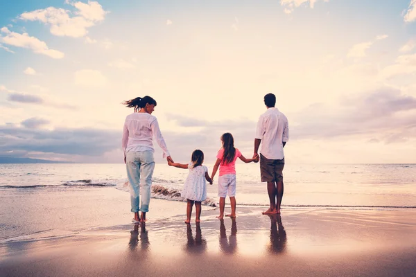 Glad ung familj på stranden vid solnedgången — Stockfoto