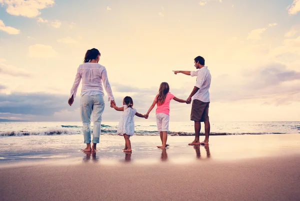 幸福年轻的家庭，在日落时分的海滩上 — 图库照片