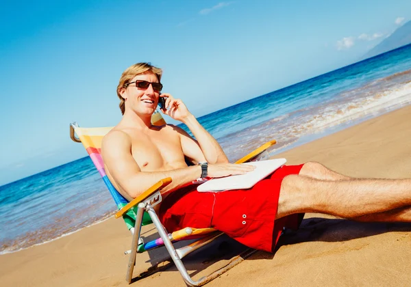 Affärsman avkopplande på stranden med bärbar dator Stockbild